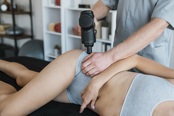 physiothérapeute utilisant un appareil de massage par percussion portable